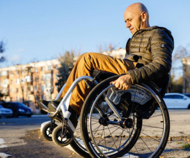 Ion Buga Dmitry Kuzuk, activista de los derechos de las personas con discapacidad en una calle transitando en su silla de ruedas. Créditos: UNDP Moldova.