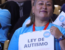 Mujer vestida con una polera celeste, sosteniendo un cartel que dice "Ley de Autismo". Fuente: Ministerio de Desarrollo Social y Familia.